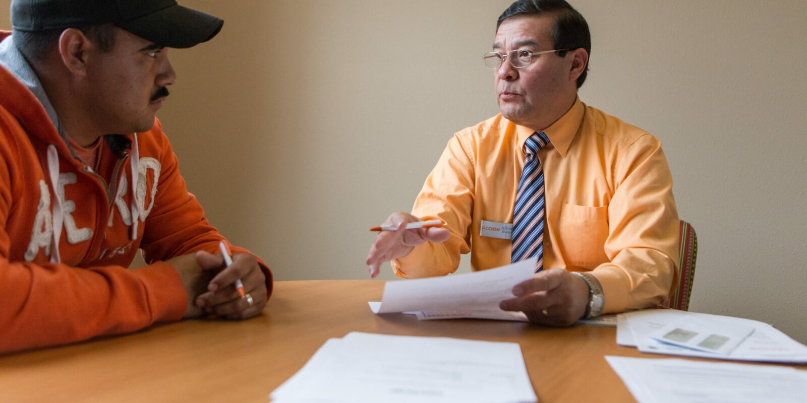 Manuel Baray goes over paperwork completing a loan for his transportation business with Accion representative, Alfonso Ramos.