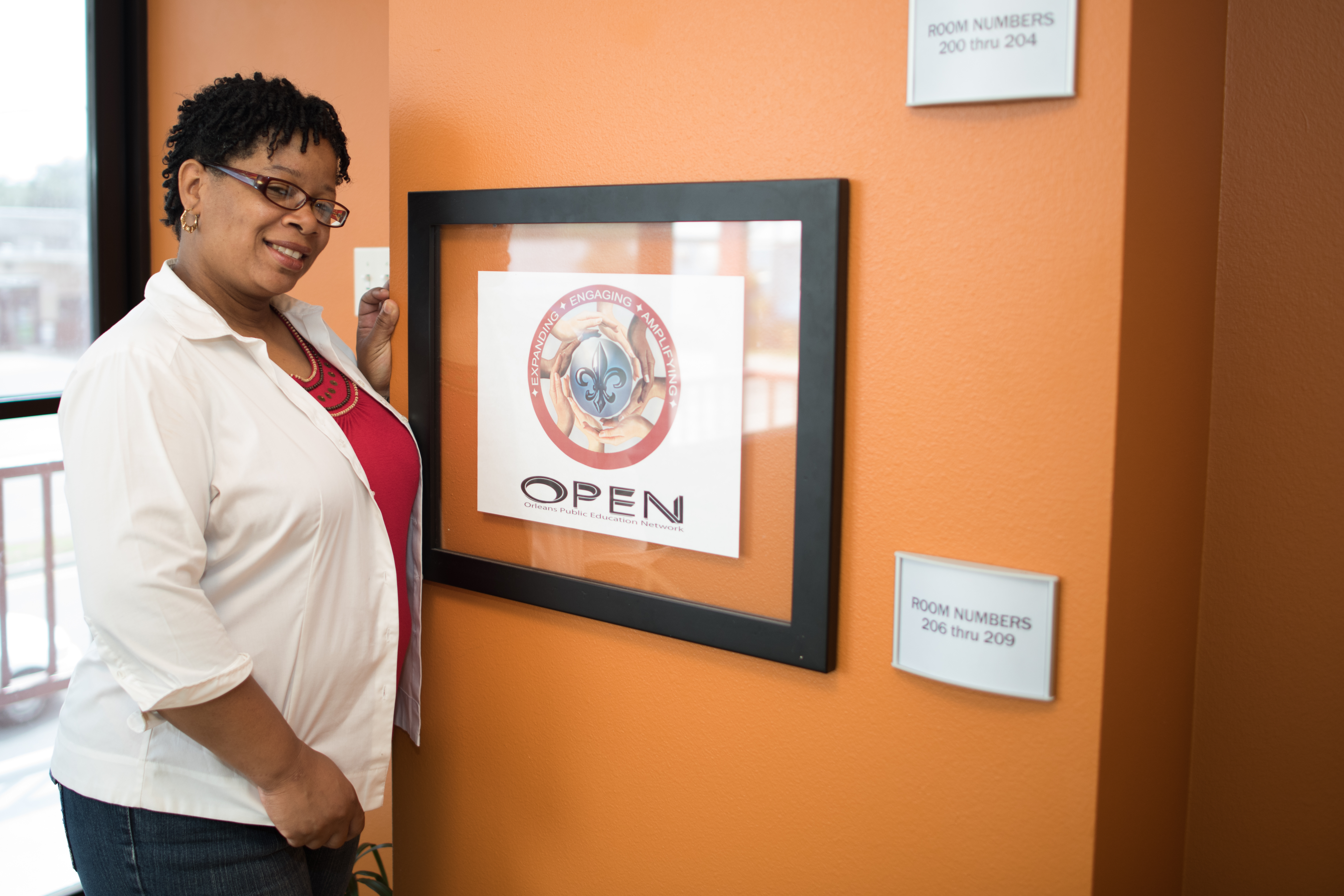 Mischell Davis stands in front of a framed sign for the Orleans Public Education Network