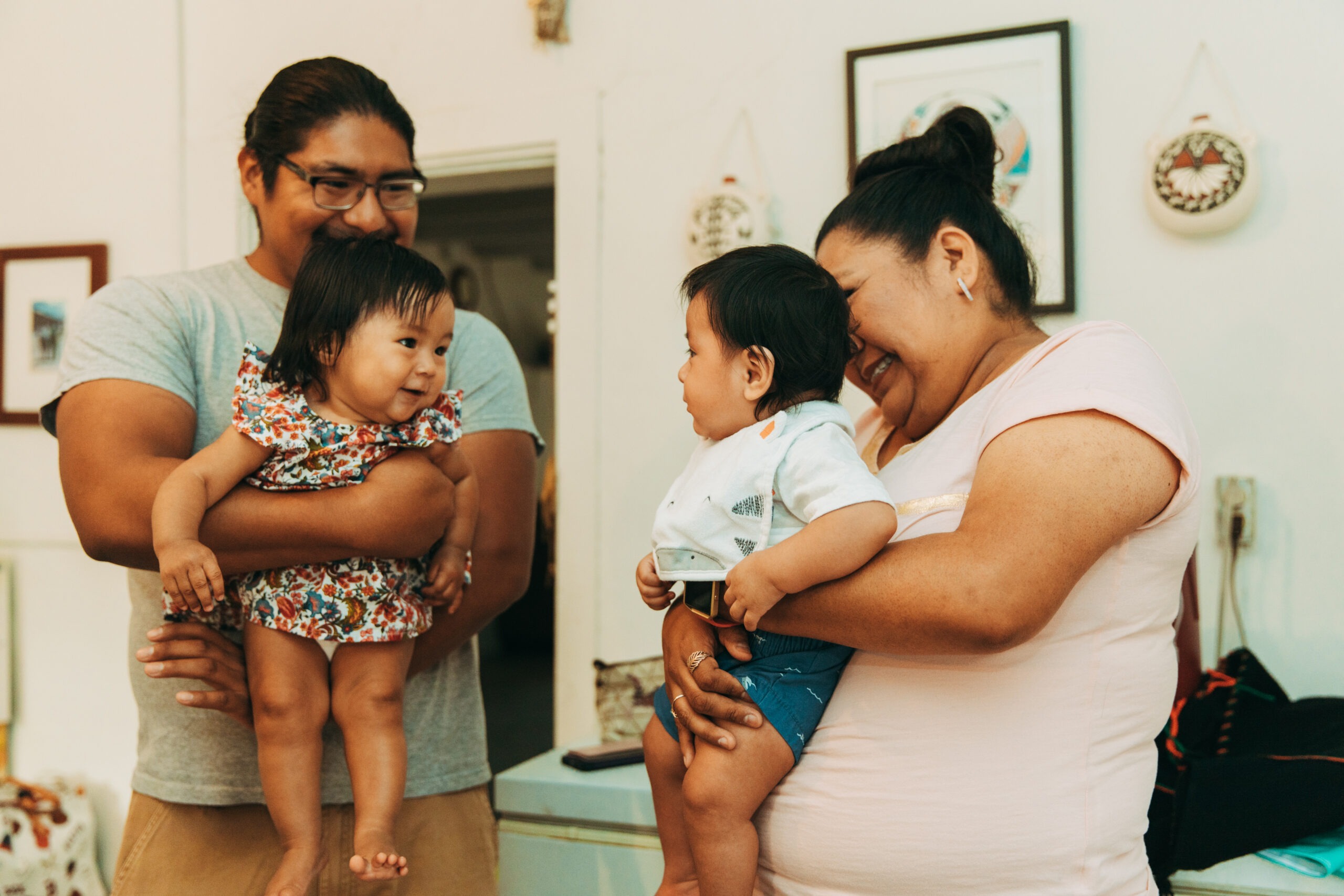 A father and a mother, each holding a young child.