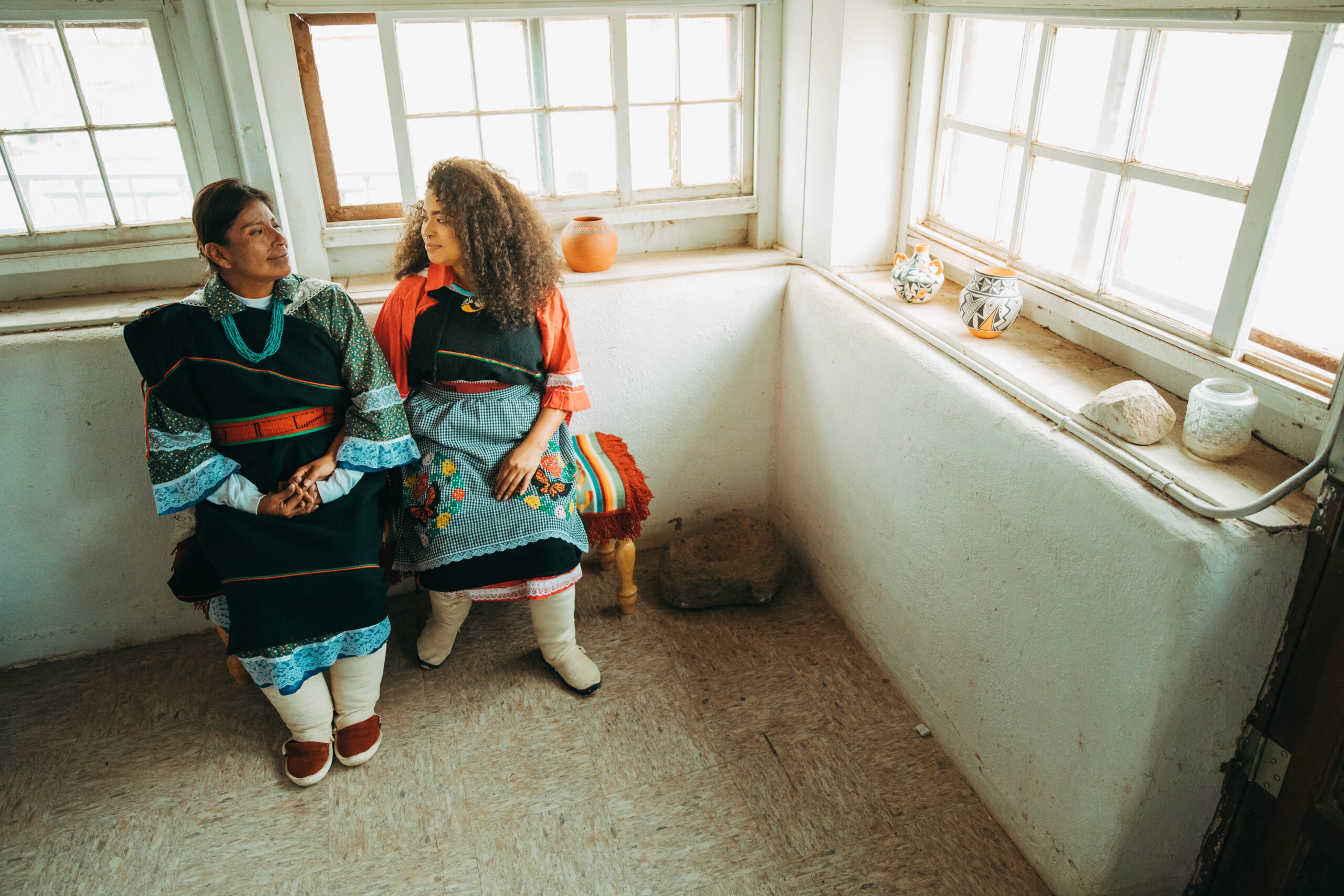 Malia Luarkie sits with another mother in traditional regalia.