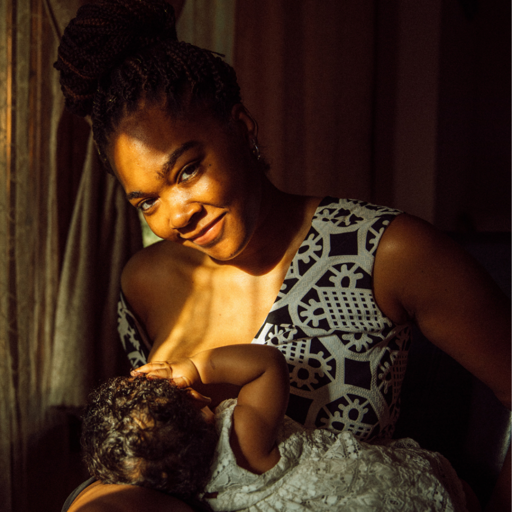 Shardaya Fuquay poses while breastfeeding her infant daughter near a window in her home