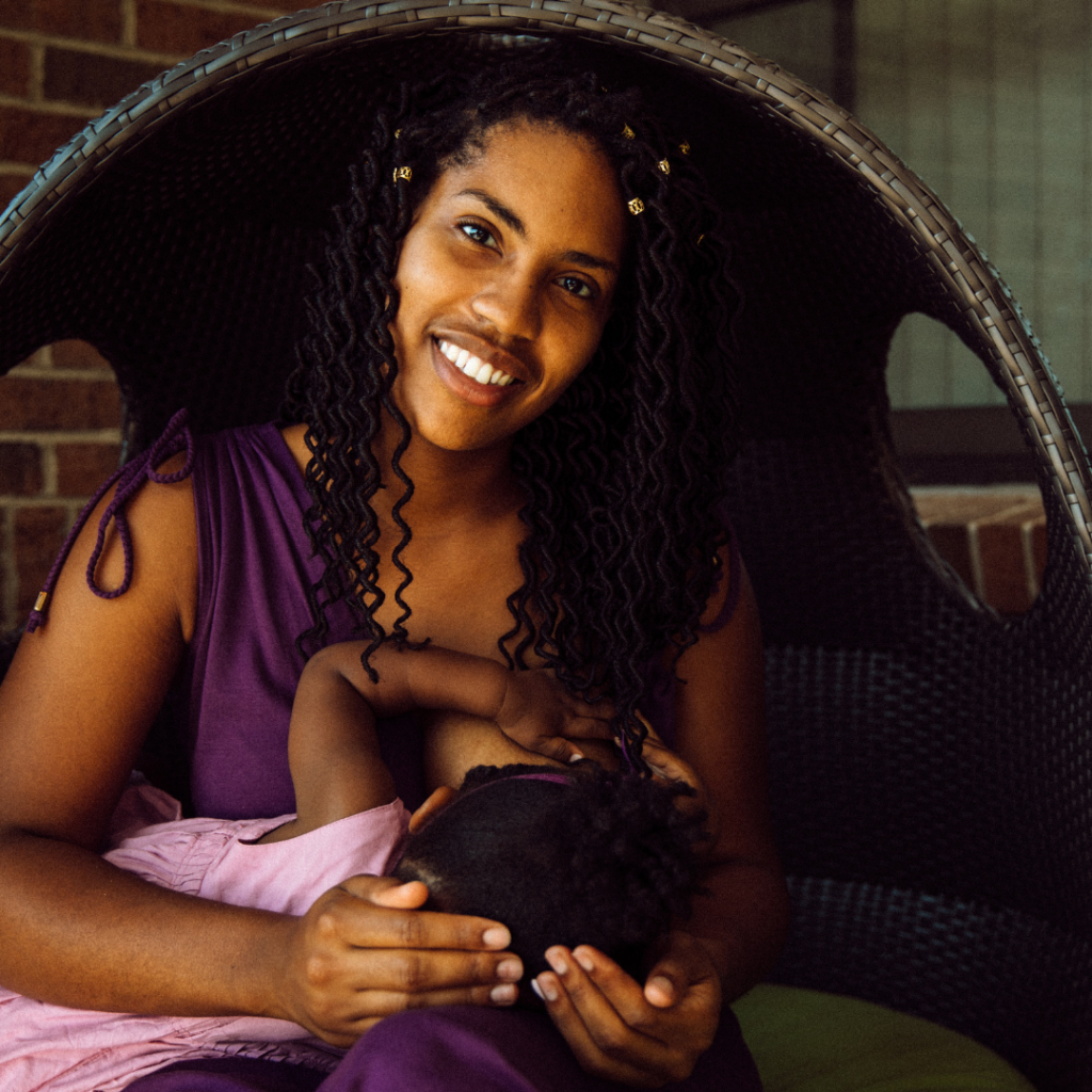 Victoria Washington breastfeeds her toddler daughter outside on patio furniture.