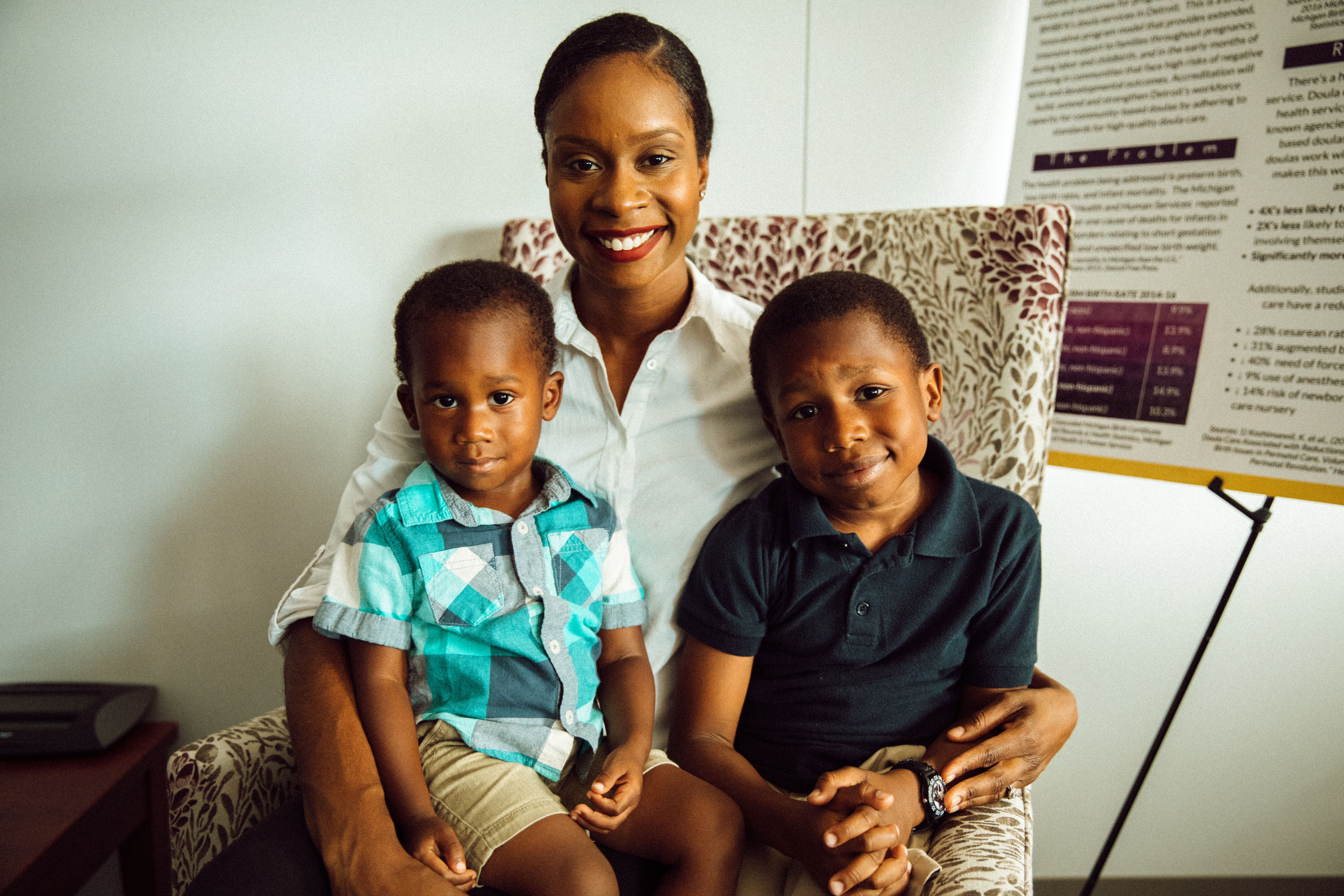 Malikah Garner sits with her two sons sitting on her lap in her office.