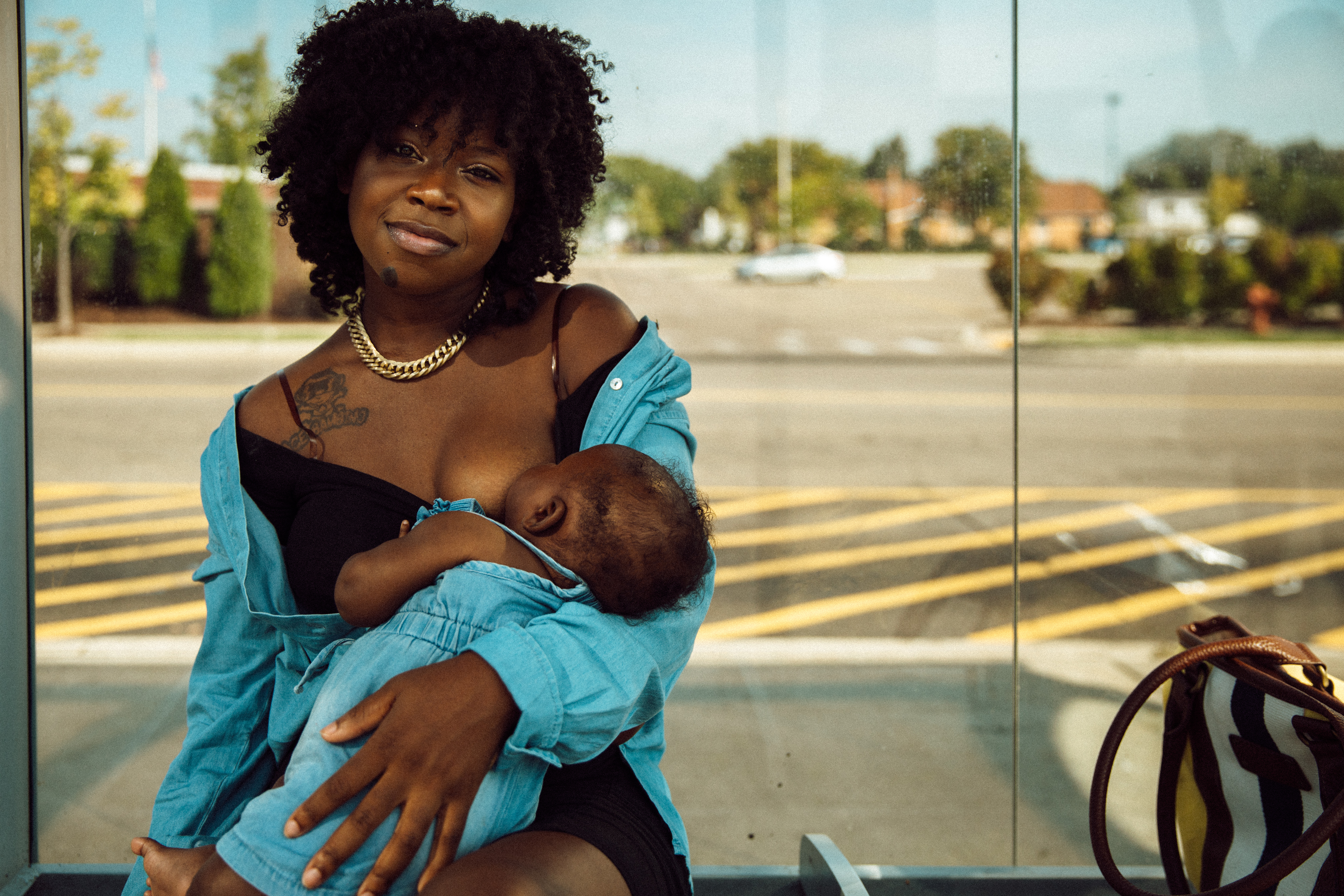 Janel Vee breastfeeds her infant daughter outside at a bus stop.