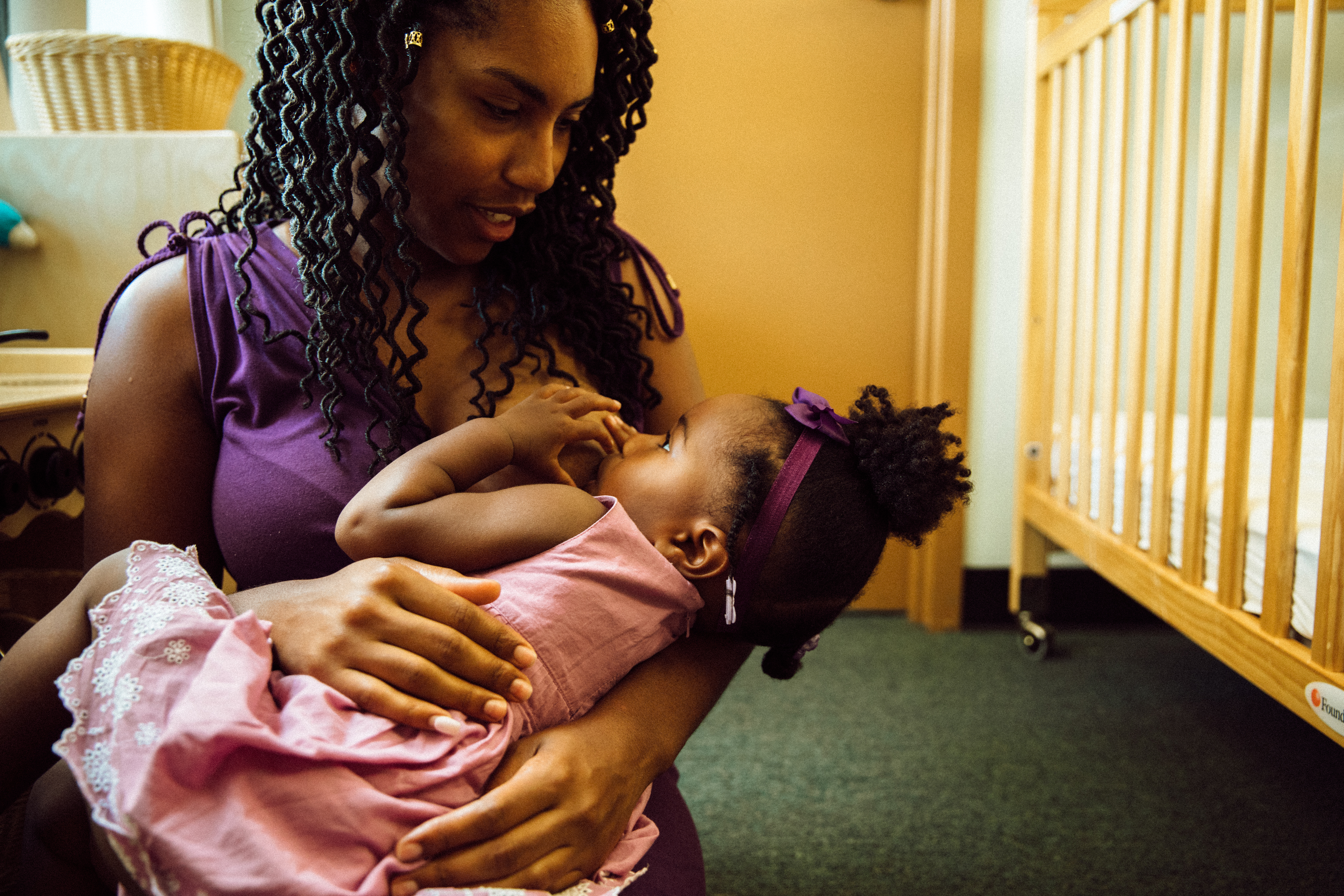 Victoria Washington kneels while holding and breastfeeding her toddler daughter at Focus: HOPE