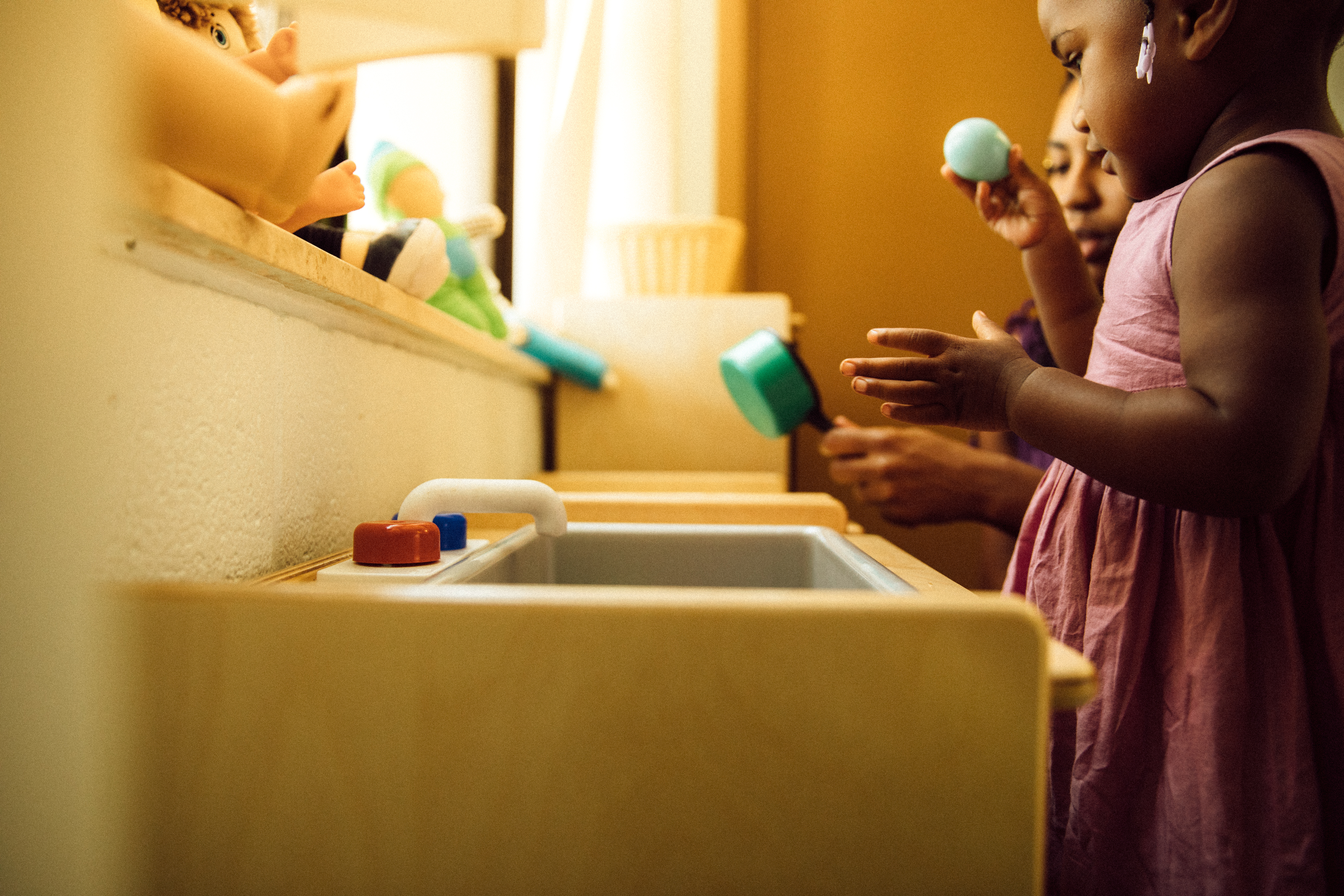 Little girl playing pretend at play kitchen sink