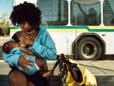 Janel Vee breastfeeds her infant daughter outside at a bus stop.