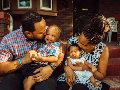 Shardaya Fuquay and her husband pose for a photo, holding their children on their front stoop.