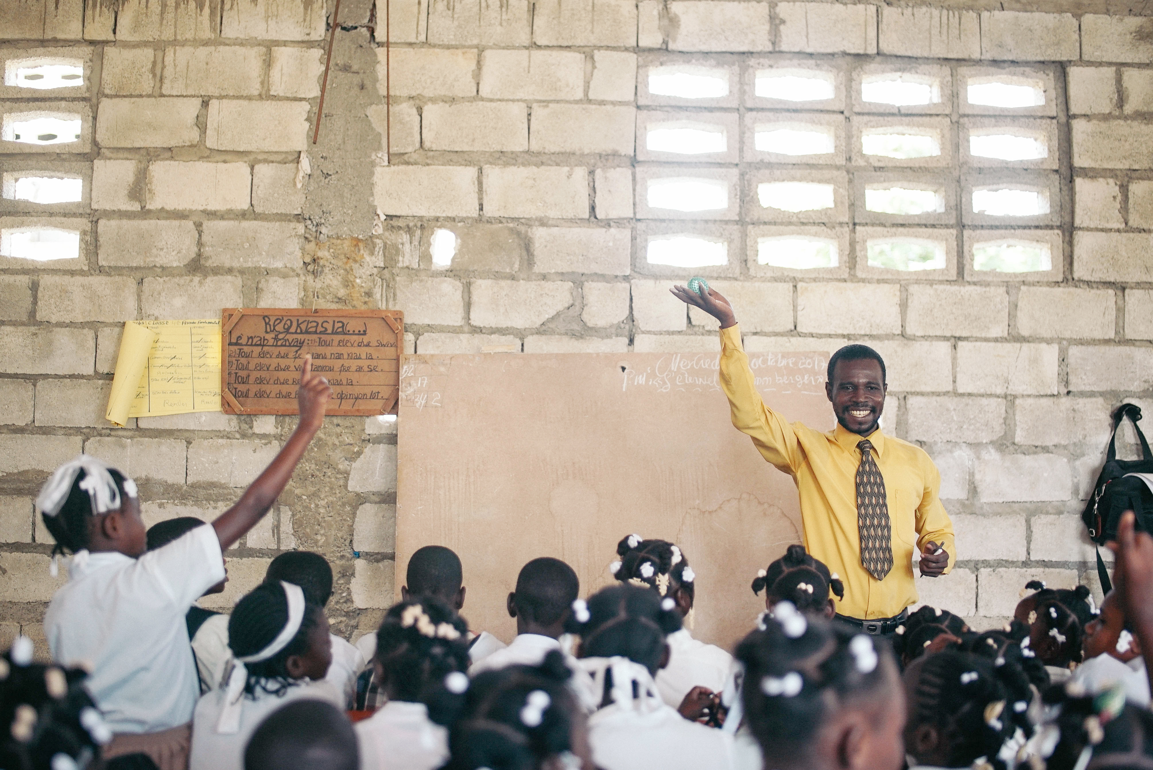 A student raises her hand in a classroom in Haiti.