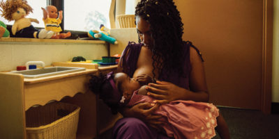 Victoria Washington holds her daughter on her lap to breastfeed.
