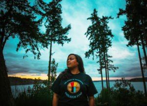 Potlatch Fund’s former Development and Communications Manager Damara Jacobs-Morris looking off to the left with the backdrop of trees and sea behind her. Potlatch Fund uplifts a longstanding native giving tradition to support community philantropy.
