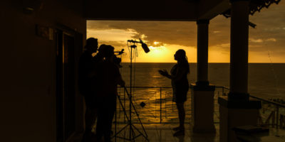 Behind the scenes with an interviewee with the sun setting in the background in Haiti.