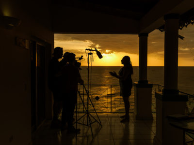 Behind the scenes with an interviewee with the sun setting in the background in Haiti.