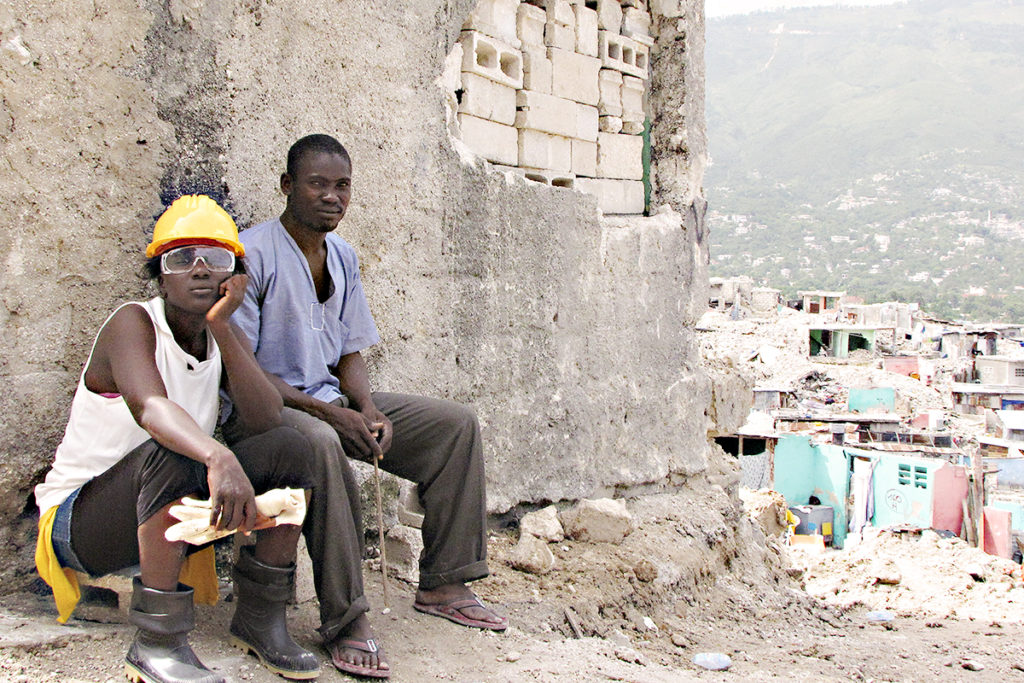 A Haitian man and woman sits among the rubble of the aftermath of the 2010 Haiti earthquake.