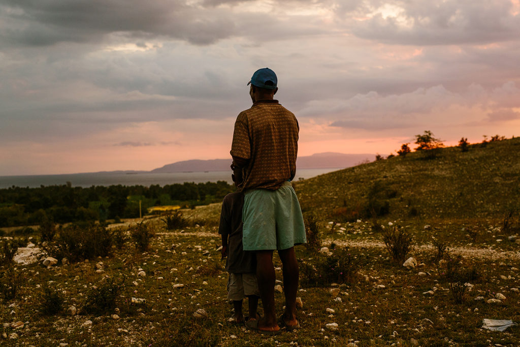 A father and son looking at the sun setting over Haiti.