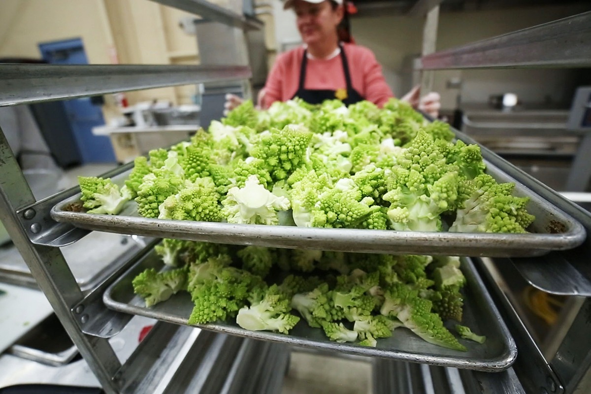 A Farm to Freezer transitional work experience employee preps Romanesco on flat trays for the freezer.