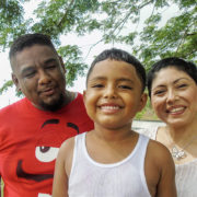 A Mexican family of three smiling.