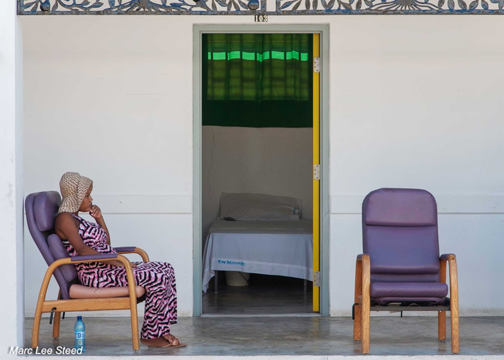 A pregnant Haitian woman sitting on a chair in the patio area at the University Hospital in Haiti.