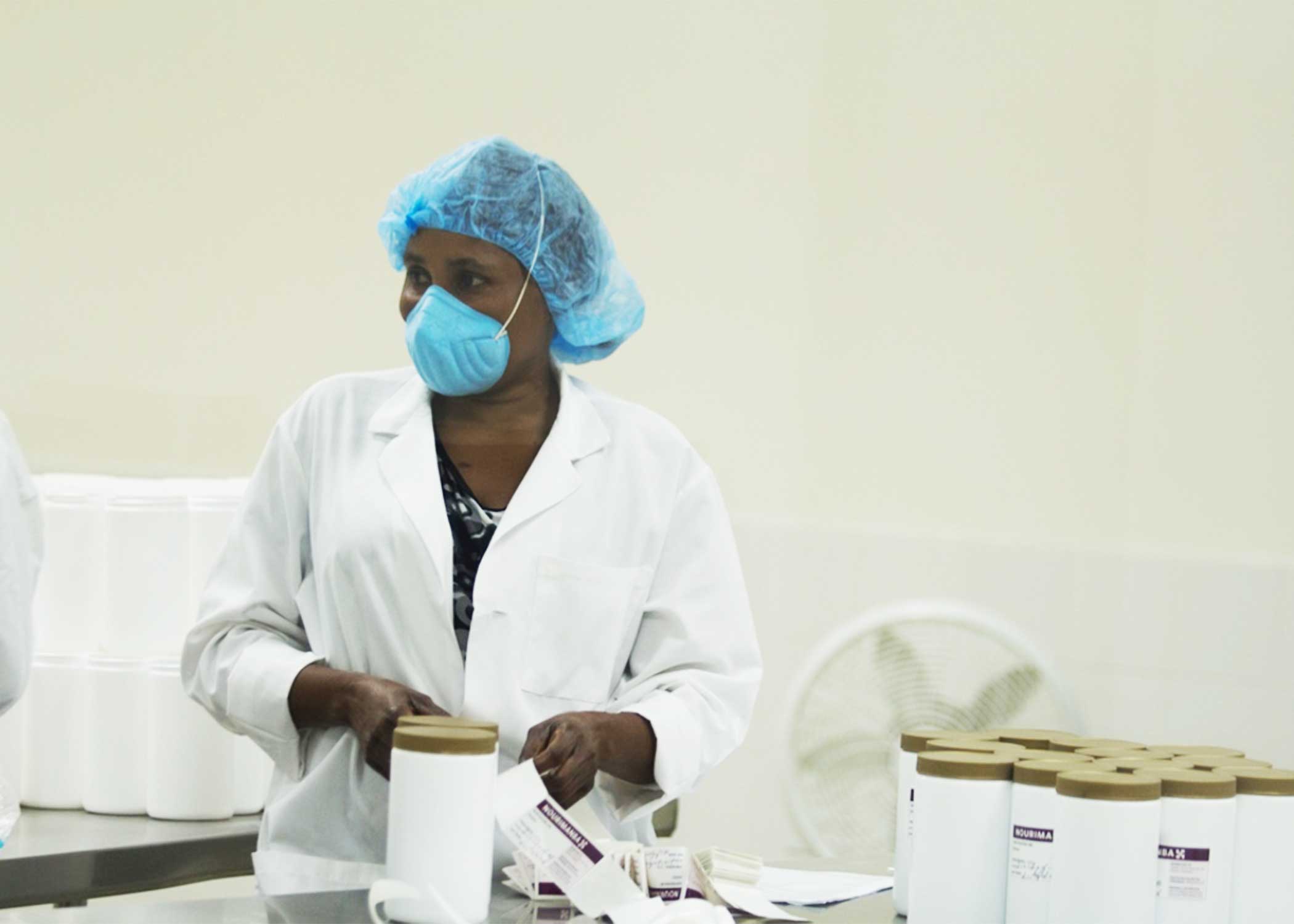 A Haitian worker in the food lab putting labels on jars of Nourimanba, the peanut-based nutritional supplement.