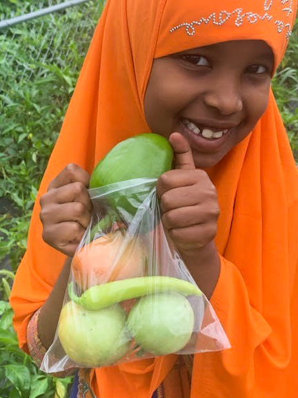 A smiling girl with her garden-fresh veggies in West Des Moines, IA. Photo courtesy of Iowa AEYC.