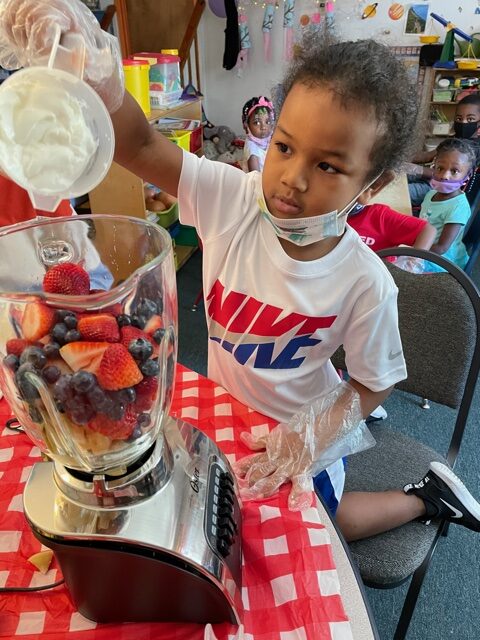 A young girl pours a cup of greek yogurt in the blender to make a healthy smoothie at Sanford Child Care Center in Lee County, NC. Photo courtesy of CEFS.