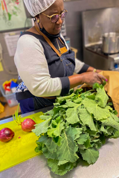 A cook prepares meals for the child care center using fresh greens and onions from the garden. Photo courtesy of Little Ones Learning Center in Forest Park, GA.