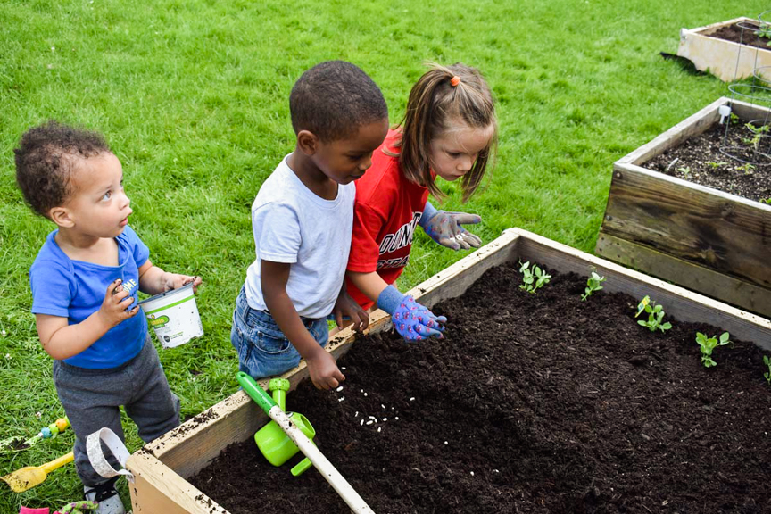 Three young gardeners are planting seeds in their garden in Sharon, PA. Photo courtesy of The Food Trust.