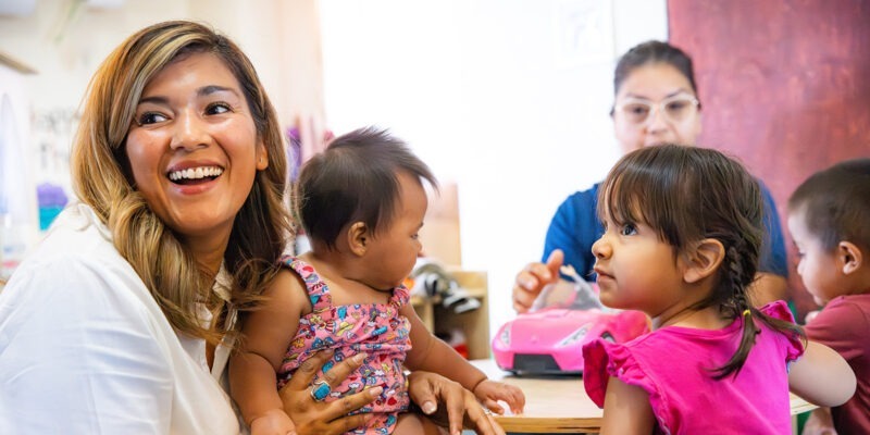 Children and caregivers sitting at table | W.K. Kellogg Foundation