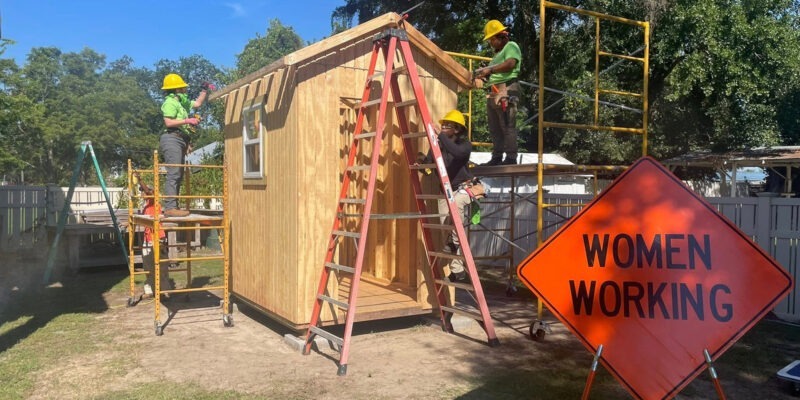 Women construction workers building a shed