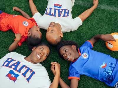 Family laying on lawn with soccer ball
