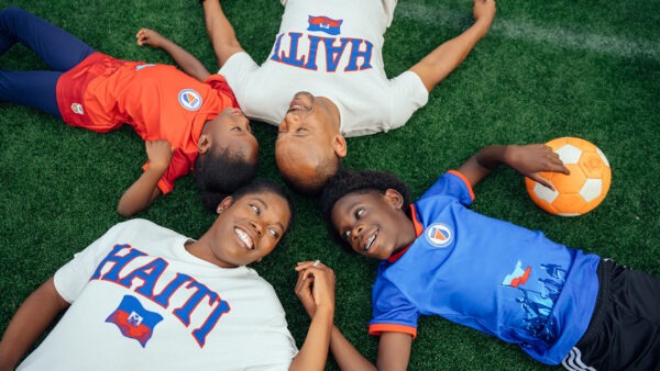 Family laying on lawn with soccer ball