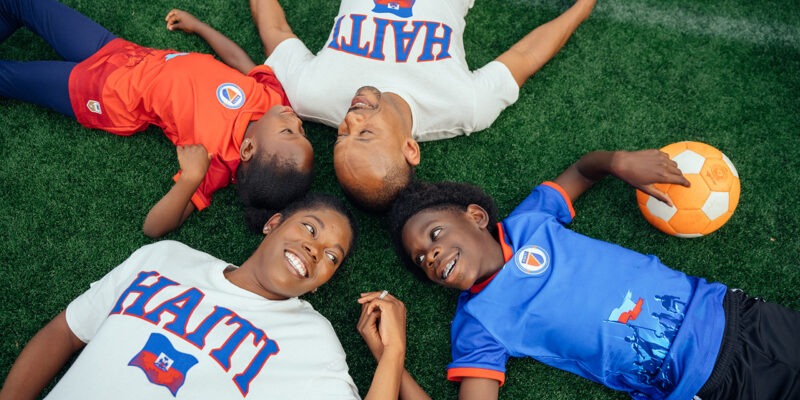 Family laying on lawn with soccer ball